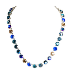 A handmade silver-tone necklace featuring a gradient of faceted round rhinestones transitioning from deep blue to light blue, teal, and amber-brown, displayed on a solid white background.
