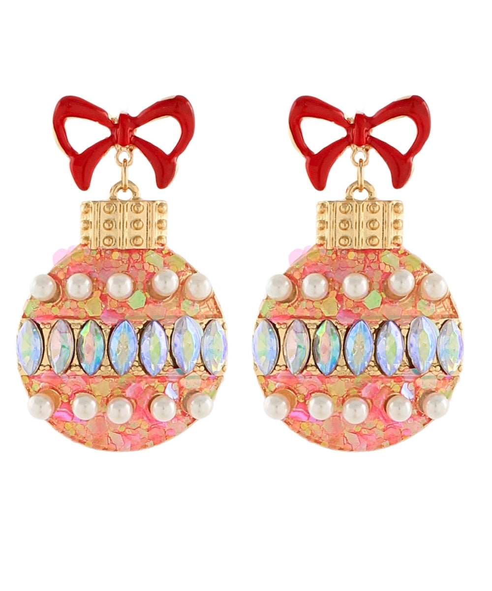 A pair of ornate Christmas ornament-shaped drop earrings with red bow tops, gold caps, and pink marbled bodies decorated with faux pearls and iridescent oval rhinestones, shown on a plain white background.